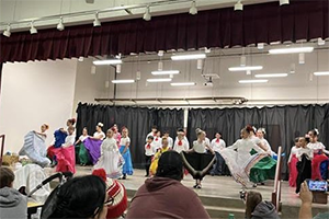 Students on stage in Folklórico costumes