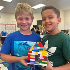 Two young boys holding their Lego creation