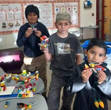 Three young boys holding their Lego creations